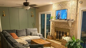 Een woonkamer met een hoekbank, een open haard en een televisie.