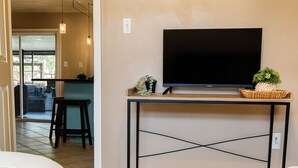 Een hotelkamer met een televisie op een houten tafel, twee bedden en uitzicht op het buitengebied.