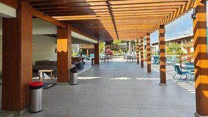 Un'area esterna coperta con travi in legno, posti a sedere e una piscina.