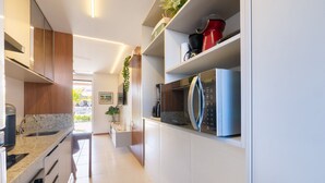 Una cucina moderna con mobili bianchi, un forno a microonde integrato e una macchina da caffè.