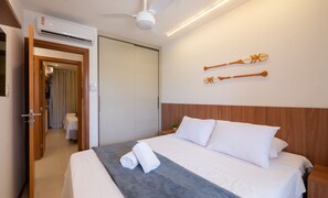 Une chambre d’hôtel avec un lit, un ventilateur de plafond et une planche de surf fixée au mur.
