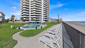 A high-rise hotel with a swimming pool, lounge chairs, and a beach view. - Horizons 202 (Daytona Beach)