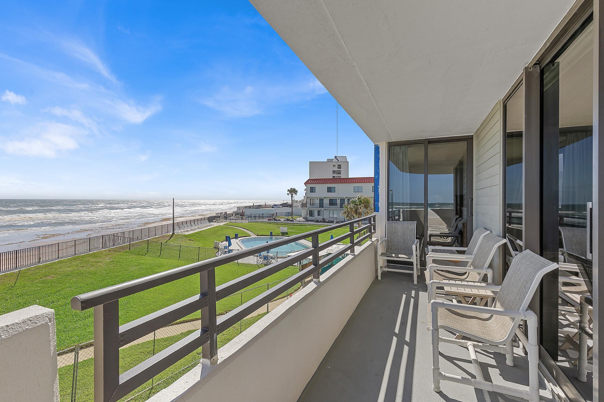 Ein Balkon mit Blick auf das Meer, ein Pool und ein Gebäude im Hintergrund.