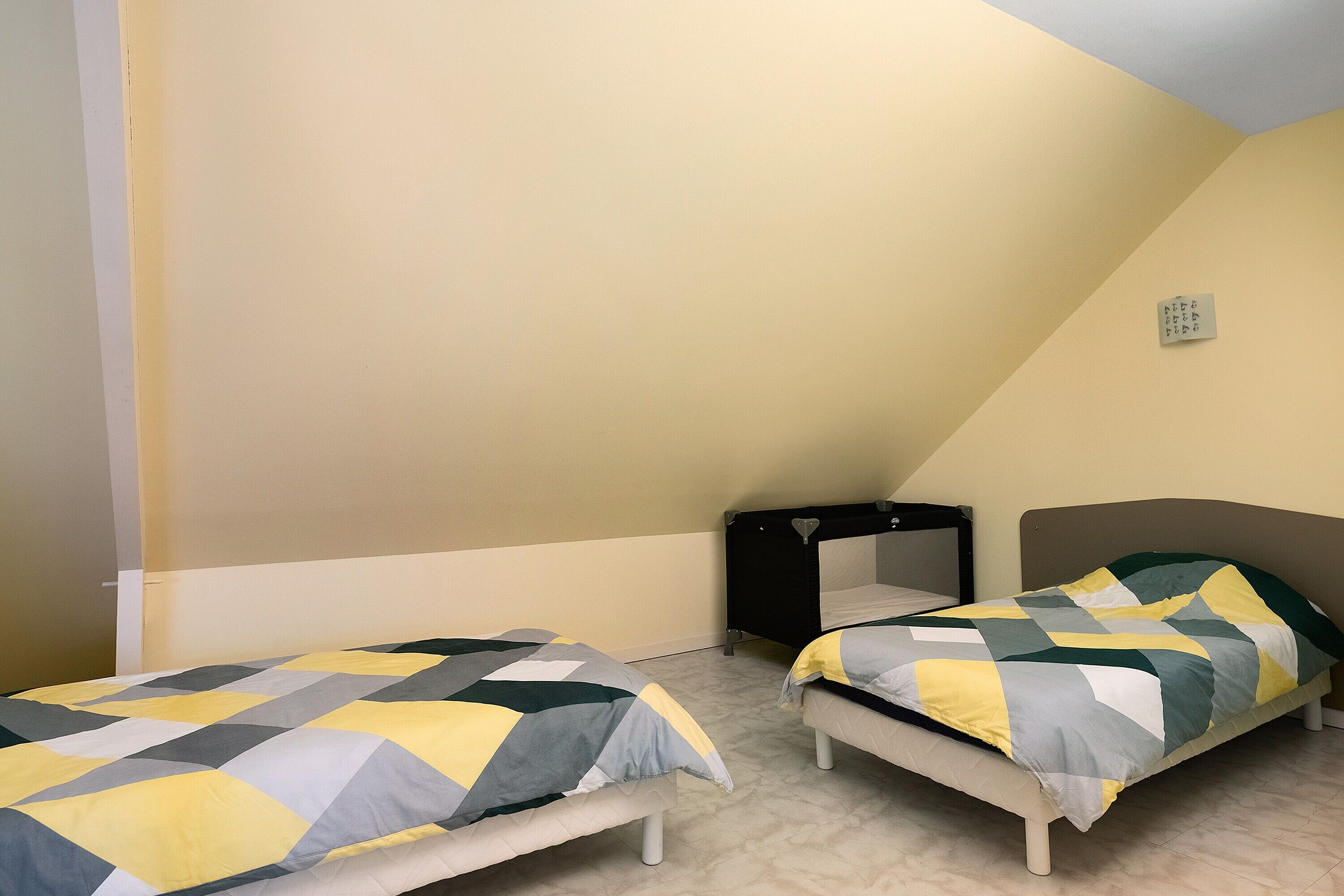 A bedroom with two beds, a black nightstand, and a small window.