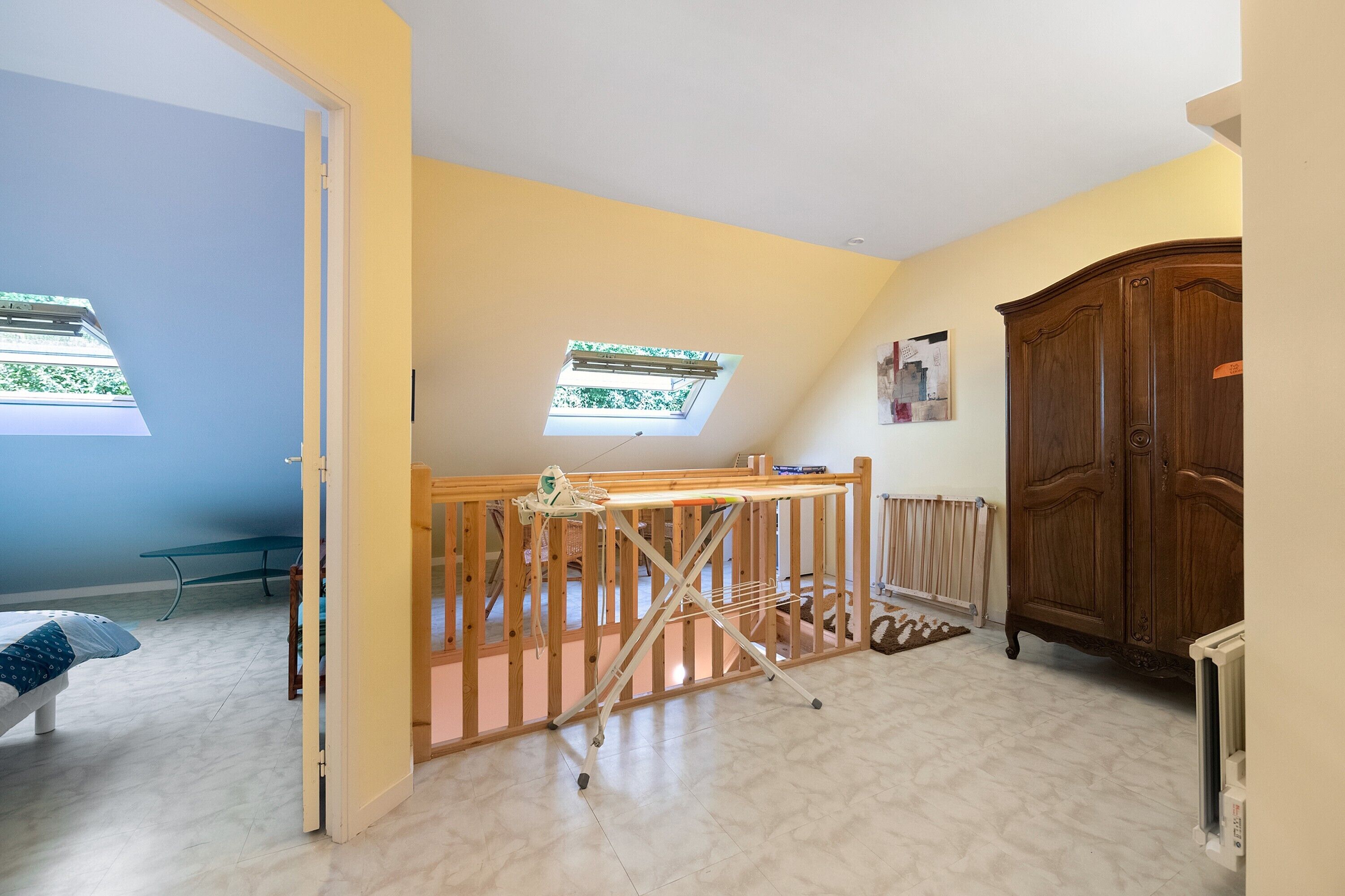 Una habitación con una cama, una mesa de madera, un armario, un radiador y un tragaluz.