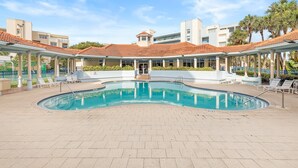 A swimming pool with a tiled deck, lounge chairs, and a covered area with columns. - Oceanwalk 11-603 (New Smyrna Beach)