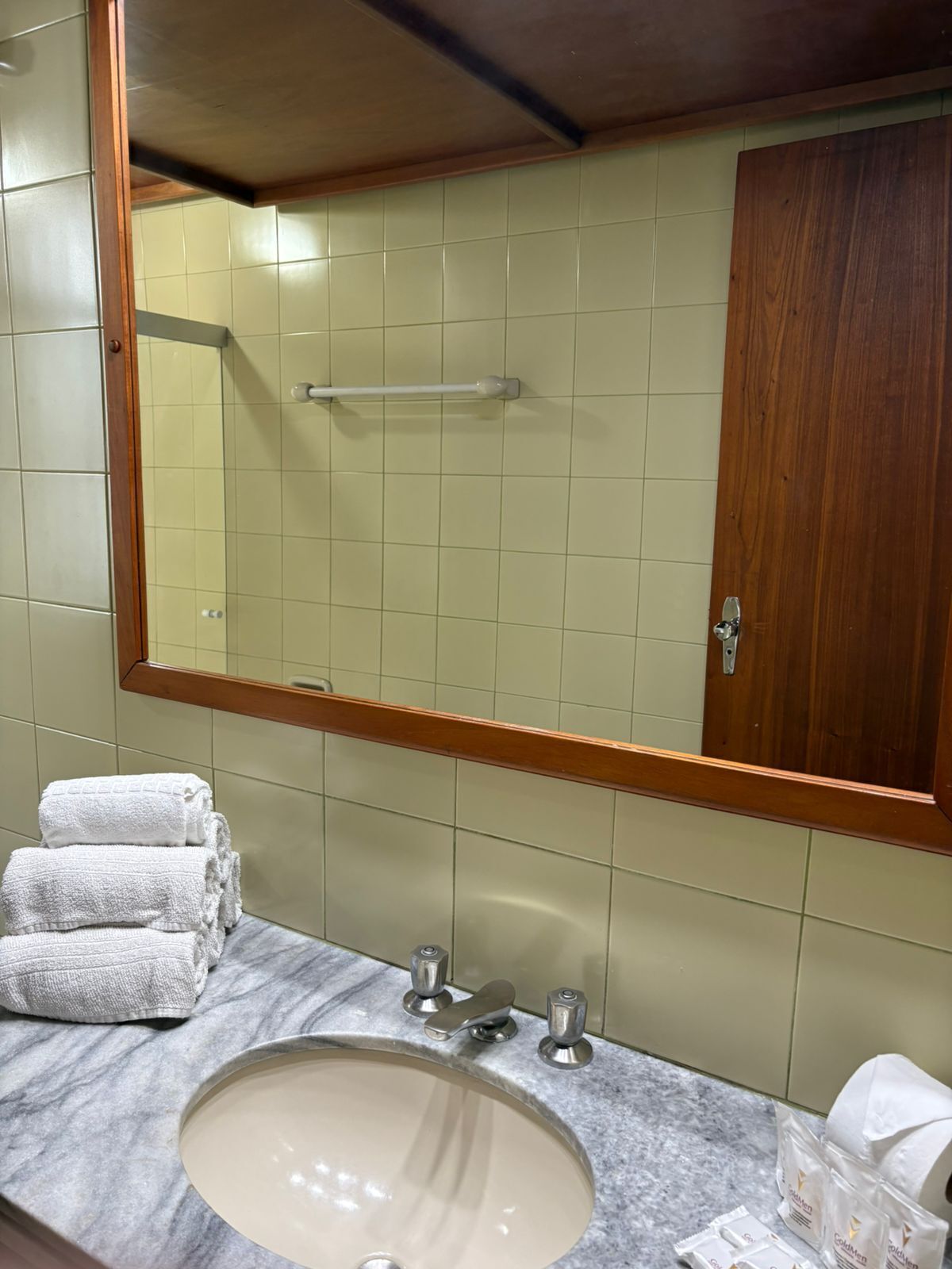 A bathroom with a marble sink, a towel rack, and a wooden door.