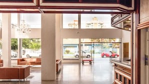 A spacious lobby with a seating area, large windows, and a view of parked cars outside. - Goldmen Business Hotel Blumenau (Blumenau)