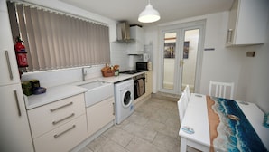 A compact kitchen with a washing machine, microwave, and a dining area with a table.