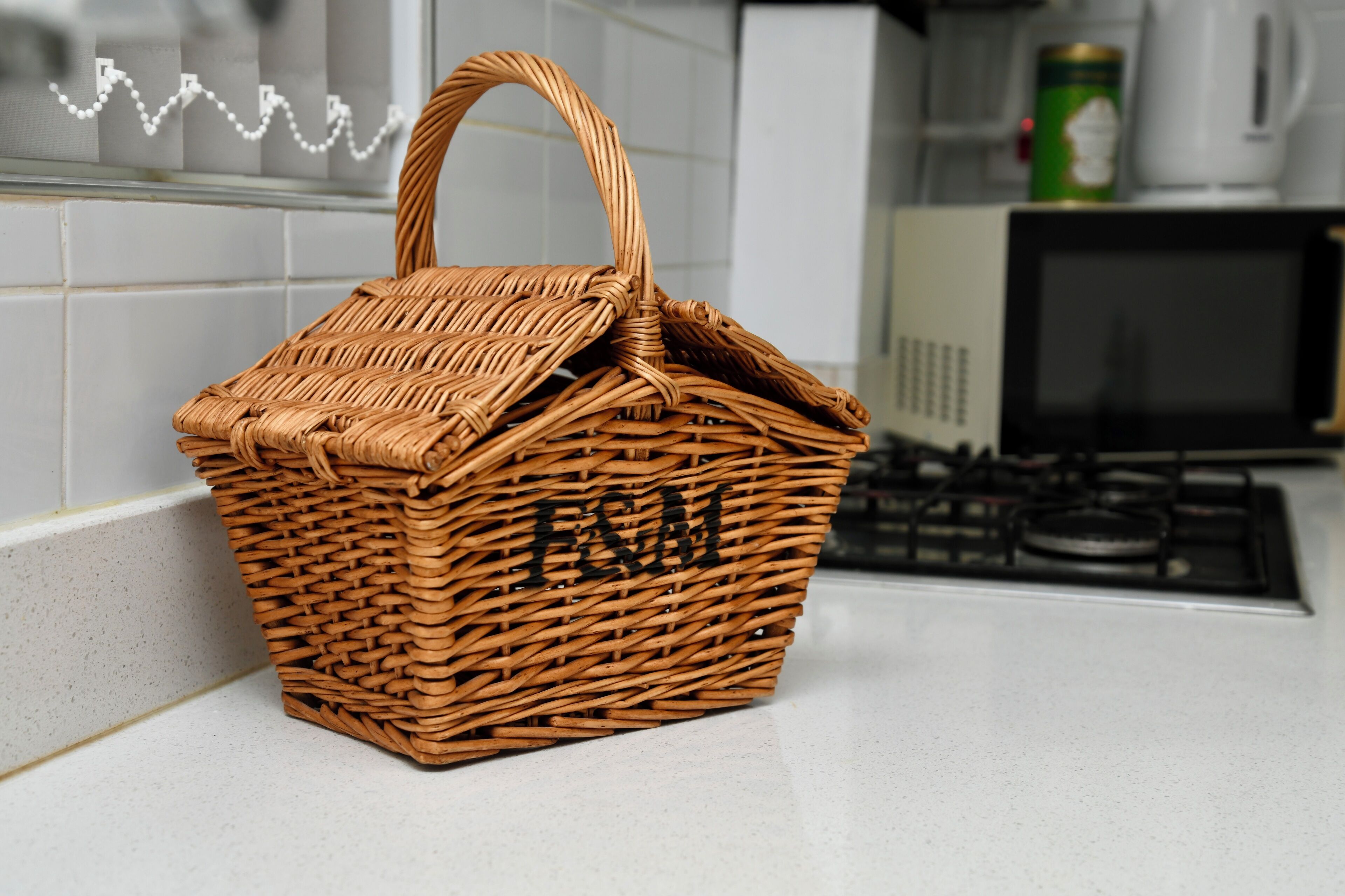 Una cesta de mimbre con asa sobre una encimera de cocina.