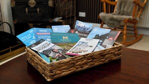 A wicker basket filled with various brochures on a wooden table.