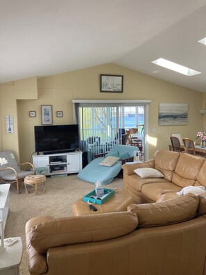A living room with a television, a sofa, a chair, and a bed. - Beautiful lake house with stunning views of  Pere Marquette and Lake Michigan (Ludington)
