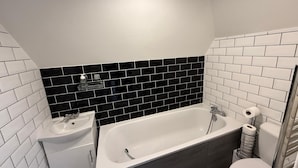 Une salle de bain moderne avec un lavabo blanc, une baignoire et des toilettes.