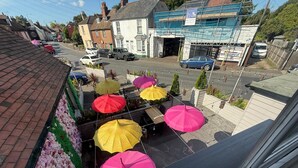 Une vue de rue avec une rangée de parasols colorés, un bâtiment en construction et des voitures garées.