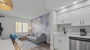 A modern kitchen with white cabinets, a stainless steel dishwasher, and a coffee maker.