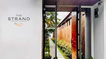 A pathway leading to a building with a sign reading 'The Strand Resort Samui.'