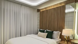 A modern bedroom with a large bed, a nightstand with a lamp, and a ceiling light. - The Strand Resort Samui  (Koh Samui)