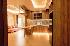 A modern kitchen with wooden cabinetry, a tiled backsplash, and a built-in oven. - The Strand Resort Samui  (Koh Samui)