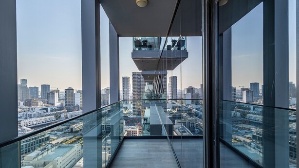 A high-rise building with a glass balcony offering a city view. - Superhost  Stylish 1BR in Bloom Tower (Dubai)