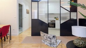 A modern kitchen with white cabinets, a black countertop, and a visible oven. - Palacio Premium Stay (Madrid)