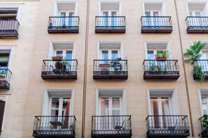 Un immeuble à plusieurs étages doté de balcons, chacun ayant une fenêtre et une petite plante.