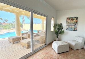 Ein Zimmer mit einer großen Schiebetür, die zu einem Poolbereich führt, einer Zimmerpflanze und einem Gemälde an der Wand.