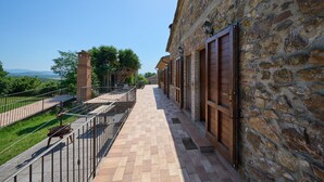 A stone building with a balcony, metal railing, and a view of the landscape. - Room 'Camera 3 - Campo Ruffaldo' with Shared Pool, Wi-Fi and Air Conditioning (Massa Marittima)