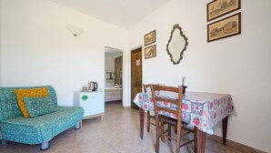 A living room with a sofa, a dining table with chairs, a coffee machine, and framed pictures on the wall. - Room 'Camera 4 - Campo Ruffaldo' with Shared Pool, Wi-Fi and Air Conditioning (Massa Marittima)