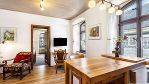 Una habitación con una mesa de comedor de madera, sillas, un televisor y obras de arte en las paredes.
