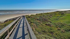 A wooden boardwalk leading to a beach with a clear view of the ocean. - Pelican Place close to beach (Port Aransas)