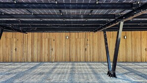 Una habitación amplia con techo alto, conductos expuestos y un panel de pared de madera.