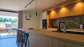 Una cocina moderna con una isla grande, taburetes de bar, horno empotrado y vistas al exterior.