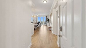 A hallway with a dining area, wooden flooring, white walls, and a ceiling light. - Ocean Place 7 ~ Shore to Please (Fernandina Beach)