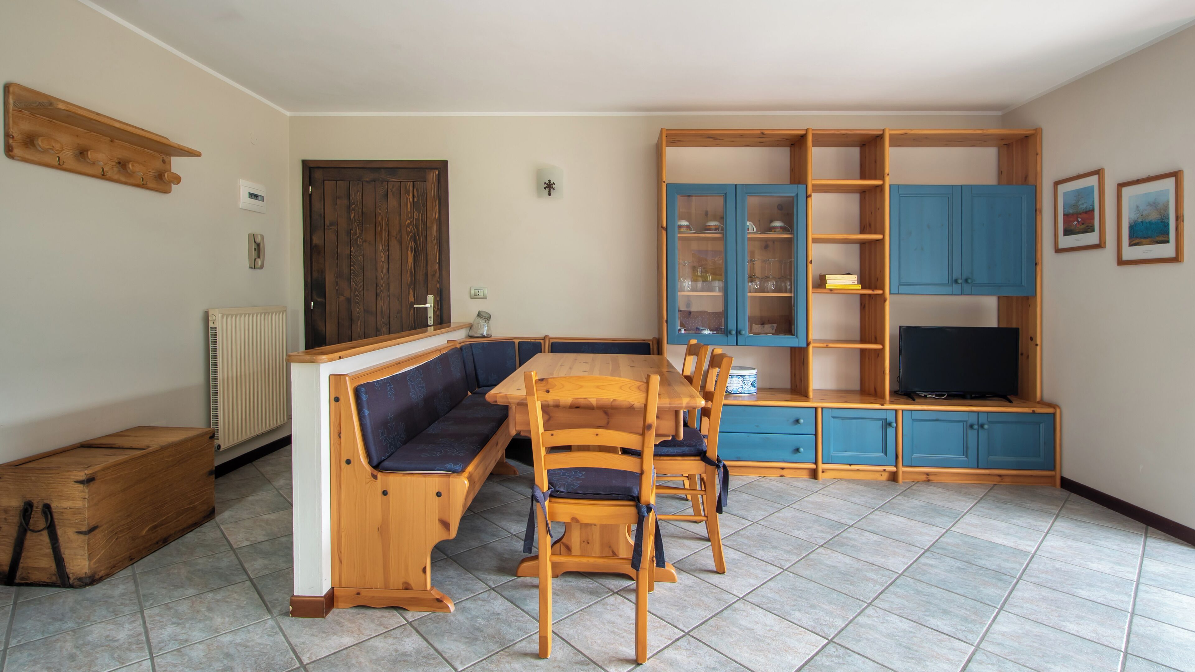 A cozy living room with a wooden bench, a dining table, and a TV stand.