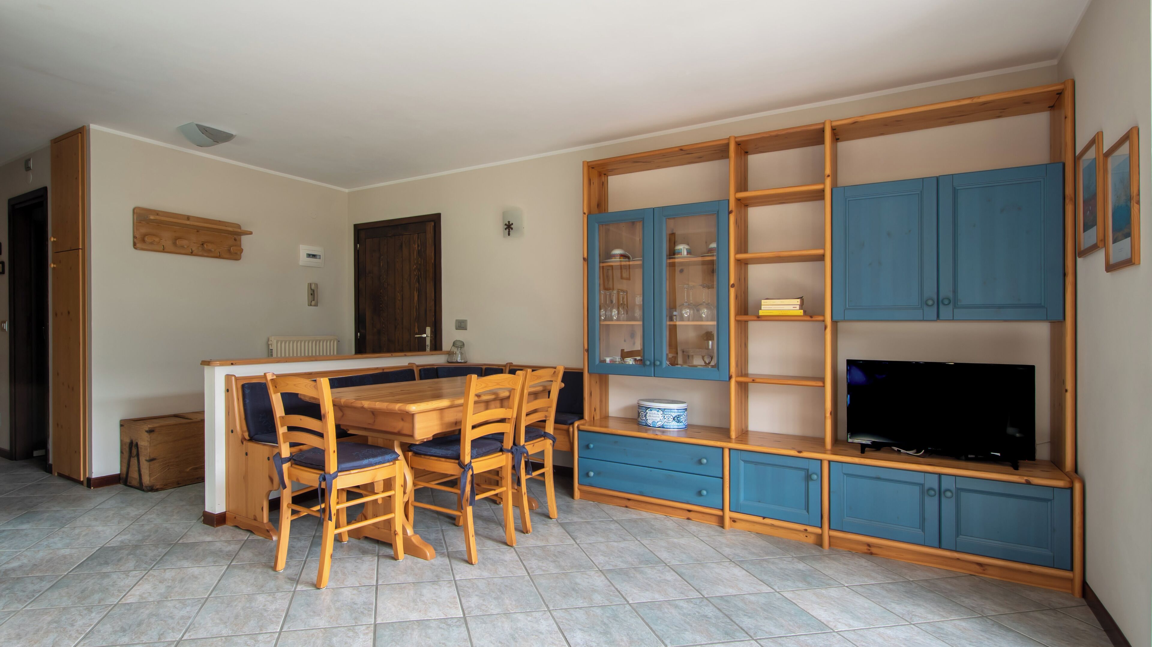 A compact living space with a dining table, chairs, a TV, and built-in storage cabinets.