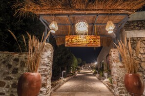 A pathway leading to a building with a rustic stone wall and a wooden archway. - Dunes and You, Pushkar - A Luxury Pool Villas Retreat (Pushkar)