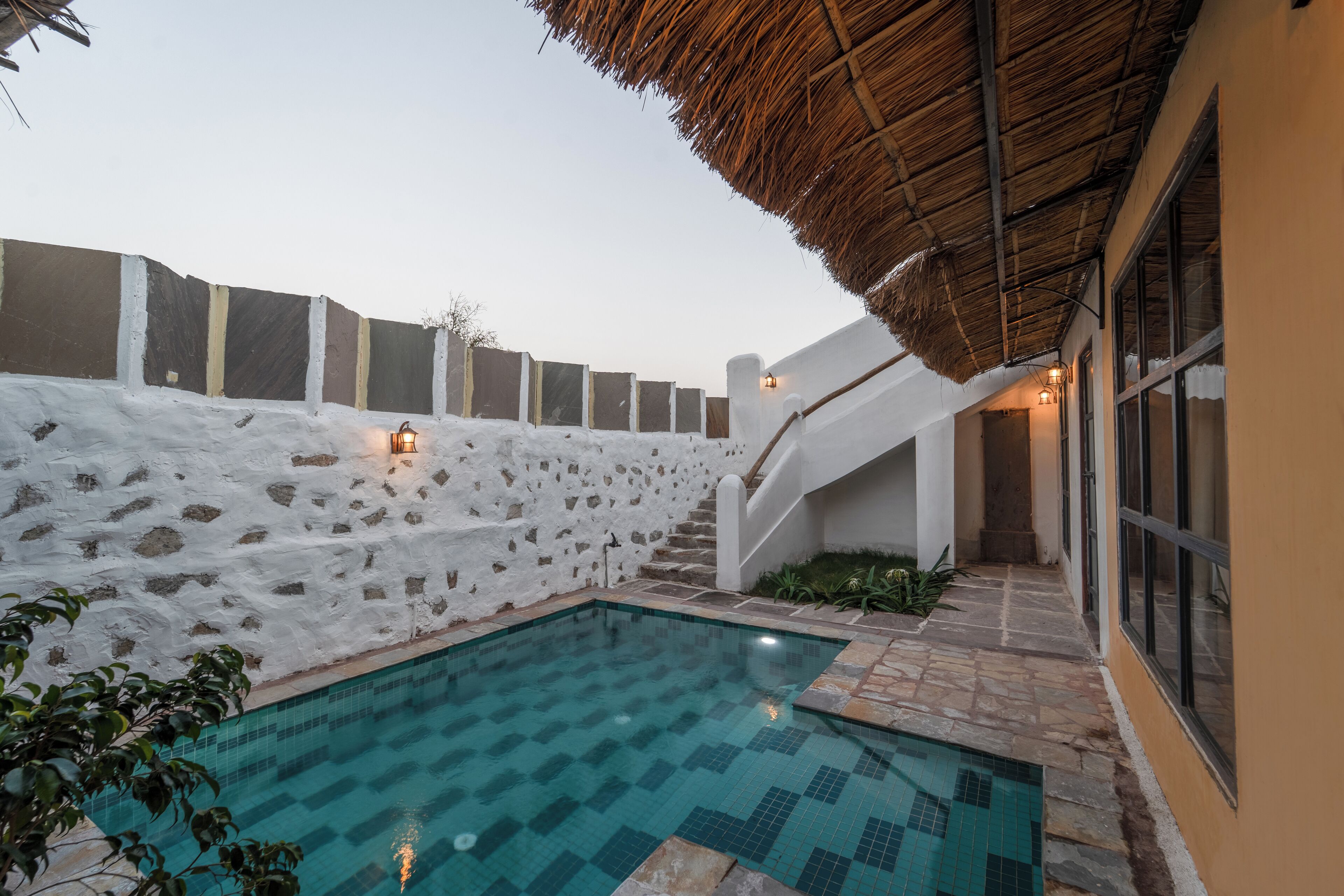 Una piscina con un muro de piedra y techo de paja.