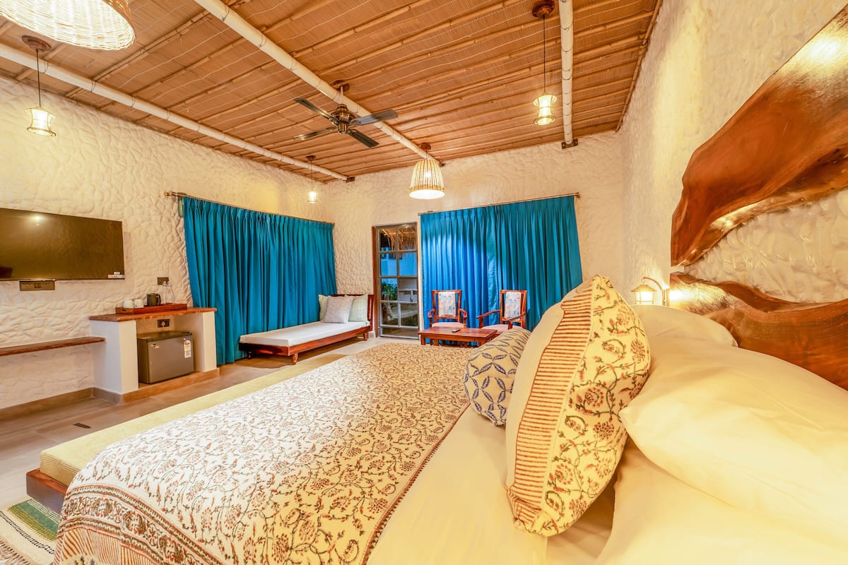 A bedroom with a large bed, a sofa, a desk, and a TV.