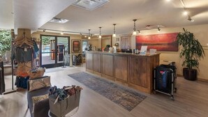A hotel lobby with a reception desk, a seating area with a patterned rug, and a large plant. - Premier 1BR + Den w/ Pool & Hot Tub Access (Keystone)