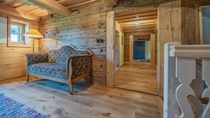 A log cabin interior with a sofa, wooden floors, and a lamp. - Holiday Home 'Englburger Hof' with Private Terrace, Private Garden and Wi-Fi (Tittling)