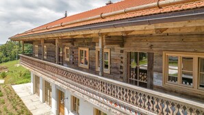A traditional wooden house with a balcony, a tiled roof, and a view of the surrounding landscape. - Holiday Home 'Englburger Hof' with Private Terrace, Private Garden and Wi-Fi (Tittling)