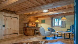 A rustic wooden interior with a desk, two chairs, a cowhide rug, and a window with curtains. - Holiday Home 'Englburger Hof' with Private Terrace, Private Garden and Wi-Fi (Tittling)