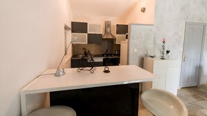 A kitchen with a white countertop, black chairs, a hanging light fixture, and a white door. - Maison l'Oustalette de Mau-bé with Pool in the Luberon (Maubec)