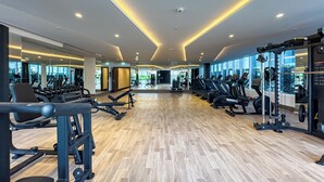 A spacious gym with various exercise equipment, large windows, and a modern design. - Superhost Spacious 1BR Arjan (Dubai)