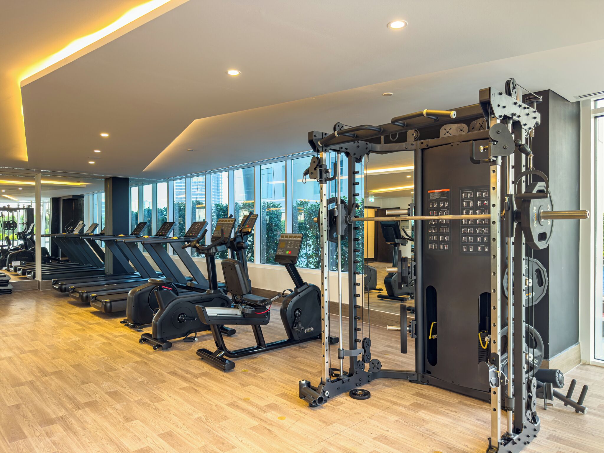 Un gimnasio moderno con cintas de correr, elípticas y equipo de levantamiento de pesas.