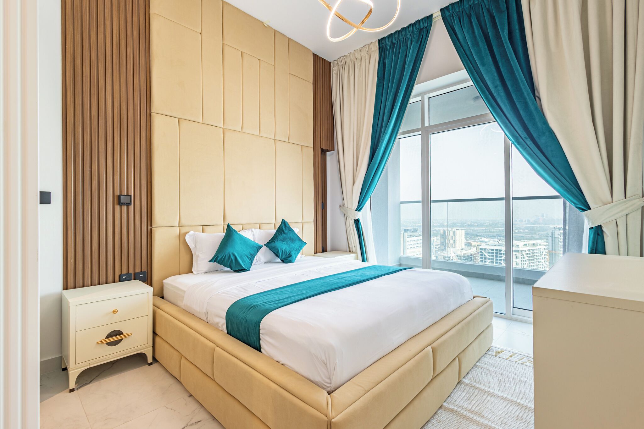 A modern hotel room with a large bed, a nightstand, and a view of the city.