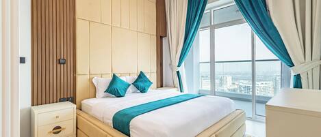 A modern hotel room with a large bed, a nightstand, and a view of the city.