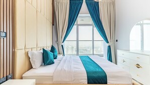 A modern hotel bedroom with a large bed, city view, and a white dresser. - Superhost Spacious 1BR Arjan (Dubai)