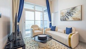 A modern living room with a sofa, armchair, and a glass coffee table. - Superhost Spacious 1BR Arjan (Dubai)
