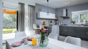 A modern kitchen with a dining area, a large window, and a view of the outdoors.